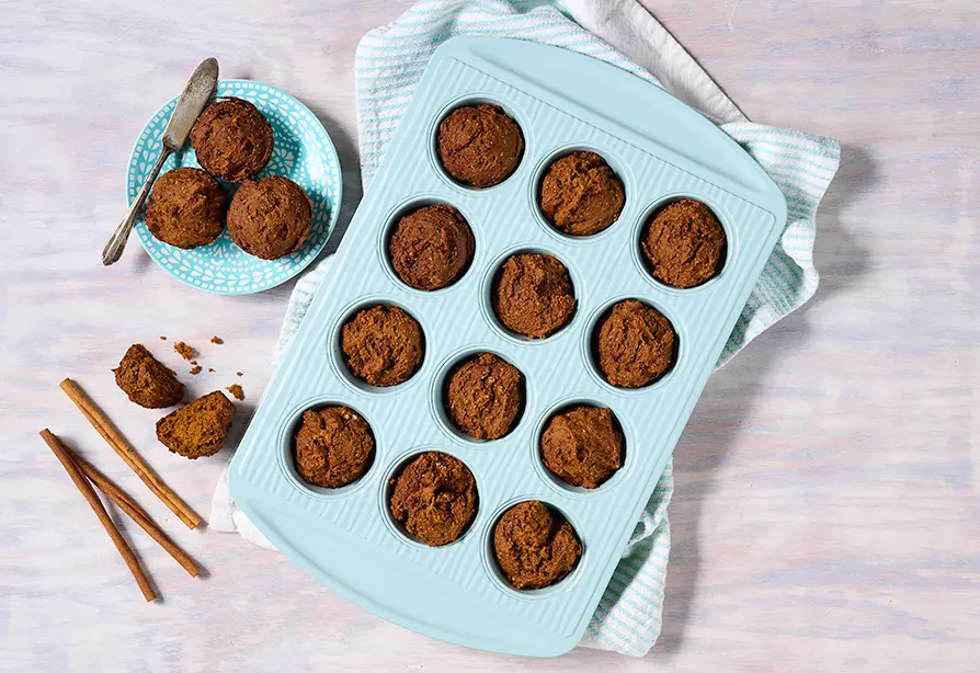 A tray and a dish with pumpkin muffins on them